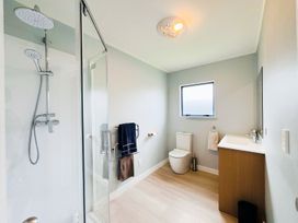 A bathroom with a shower, toilet, and sink at La Maison Bleu - Mangawhai Heads Holiday Home, Mangawhai