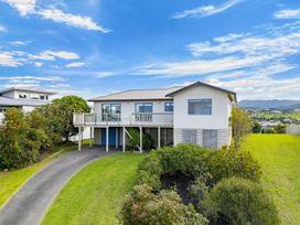 A house with a deck and garage at La Maison Bleu - Mangawhai Heads Holiday Home Mangawhai