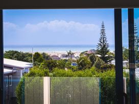 A view of the ocean and trees from a window at La Maison Bleu - Mangawhai Heads Holiday Home, Mangawhai