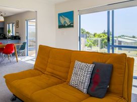 A living room with a sofa and dining area at La Maison Bleu - Mangawhai Heads Holiday Home, Mangawhai