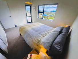 A bedroom with a bed and a window at La Maison Bleu - Mangawhai Heads Holiday Home, Mangawhai