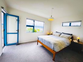 A bedroom with a bed and nightstand at La Maison Bleu - Mangawhai Heads Holiday Home, Mangawhai