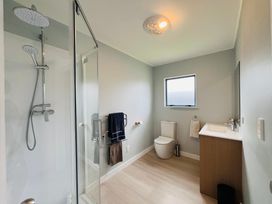 A bathroom with shower, toilet, and sink at La Maison Bleu - Mangawhai Heads Holiday Home, Mangawhai