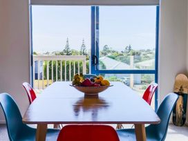 A dining table with a fruit bowl and chairs at La Maison Bleu - Mangawhai Heads Holiday Home Mangawhai