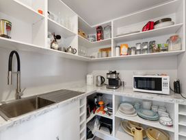 A kitchen with a sink, coffee machine, microwave, and various dishes at Turangi Holiday Home in Turangi
