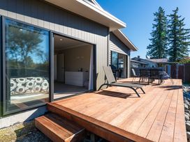 A deck with a dining table and lounge chairs at Turangi Holiday Home in Turangi