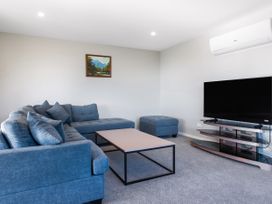 A living room with a sofa and television at Bay View Escapse - Cable bay Holiday Home