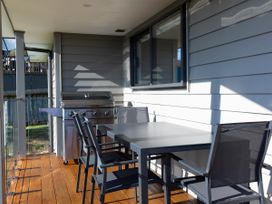 A patio area with a table and chairs and a barbecue grill at Bay View Escape - Cable Bay