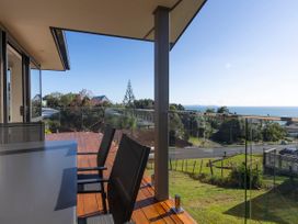 A deck with outdoor table and chairs at Bay View Escape - Cable Bay