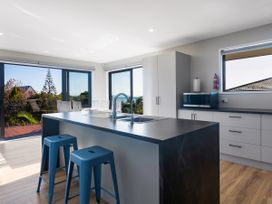 A kitchen with a sink and stools at Bay View Escape - Cable Bay