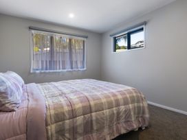 A bedroom with a bed and windows at Bay View Escape - Cable Bay