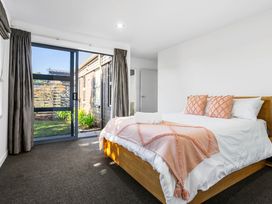 A bedroom with a bed and a window at Sun & Surf Stay - Papamoa Holiday Home