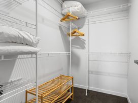 A closet with shelves and hangers at Sun & Surf Stay - Papamoa Holiday Home