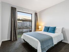 A bedroom with a bed and bedside table at Sun & Surf Stay - Papamoa Holiday Home