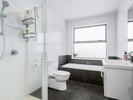 A bathroom with a shower, toilet, bathtub and sink at Sun & Surf Stay - Papamoa Holiday Home