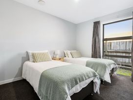 A bedroom with two single beds and a nightstand at Sun & Surf Stay - Papamoa Holiday Home