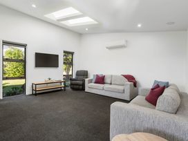 A living room with couches and a television at Sun & Surf Stay - Papamoa Holiday Home