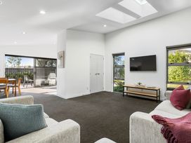 A living room with a television and sliding door at Sun & Surf Stay - Papamoa Holiday Home