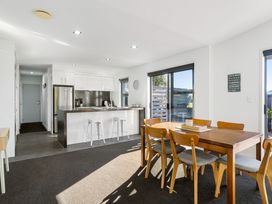 A kitchen with a dining table and chairs at Sun & Surf Stay - Papamoa Holiday Home