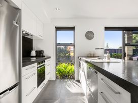 A kitchen with appliances and a window at Sun & Surf Stay - Papamoa Holiday Home