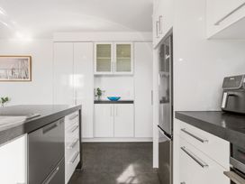 A kitchen with a refrigerator, sink, and cabinets at Sun & Surf Stay - Papamoa Holiday Home