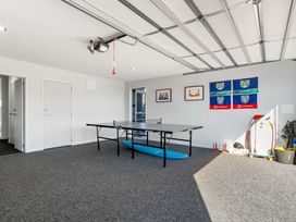 A garage with a ping pong table and surfboards at Sun & Surf Stay - Papamoa Holiday Home