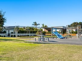 A playground with swings and a slide at Sun & Surf Stay - Papamoa Holiday Home