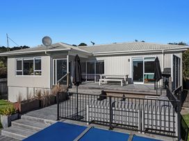 An outdoor view of a house with a deck and furniture at Ocean Breeze Escape - Ohope Holiday Home