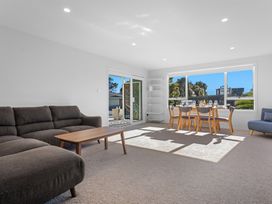 A living room with a sofa, dining table and chairs at Ocean Breeze Escape - Ohope Holiday Home