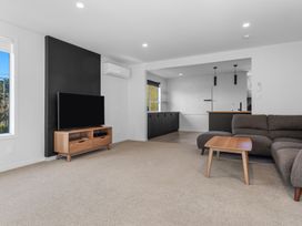 A living room with a television on a stand and a sofa at Ocean Breeze Escape - Ohope Holiday Home
