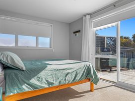 A bedroom with a bed and window leading to a deck at Ocean Breeze Escape - Ohope Holiday Home