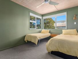 A bedroom with two beds and windows at Ocean Breeze Escape - Ohope Holiday Home