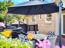 A garden with a table and chairs under an umbrella at Lola's - Cambridge Holiday Home, Morrinsville
