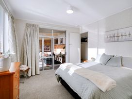 A bedroom with a bed and sliding door at Lola's - Cambridge Holiday Home in Morrinsville