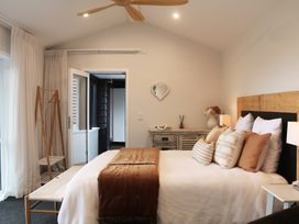 A bedroom with a bed and dressing table at Country Idyll II – Sandspit Holiday Cottage in Warkworth