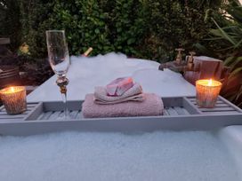 An outdoor bath area with a bathtub, towel, soap, and candles at Country Idyll Hut 2 – Sandspit Holiday Cottage, Sandspit