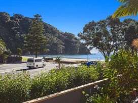 A view of the beach and ocean with flowers and a parked vehicle at The Lights House - Beachfront Ohope Holiday Home Ohope