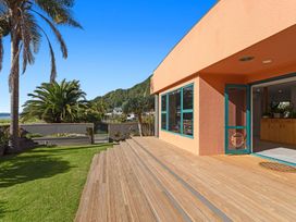 An outdoor area with a wooden deck and palm trees at The Lights House - Beachfront Ohope Holiday Home Ohope