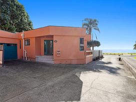 A house with a garage and palm trees at The Lights House - Beachfront Ohope Holiday Home Ohope
