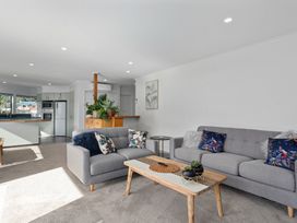 A living room with a sofa, coffee table, and kitchen area at The Lights House - Beachfront Ohope Holiday Home Ohope