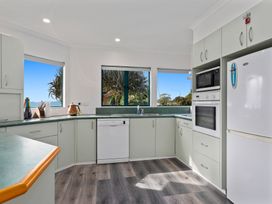 A kitchen with cabinets and appliances at The Lights House - Beachfront Ohope Holiday Home Ohope