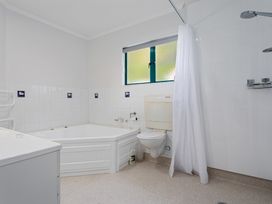 A bathroom with a bath tub, toilet and shower at The Lights House - Beachfront Ohope Holiday Home Ohope