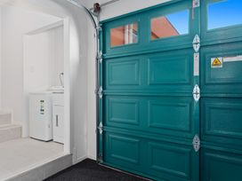 A garage with a washing machine and a teal garage door at The Lights House - Beachfront Ohope Holiday Home Ohope