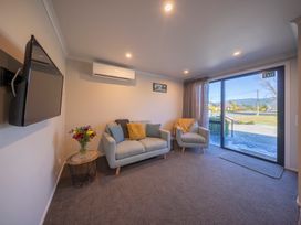 A living room with sofas and a television at Mustering - Te Anau Holiday Home in Te Anau