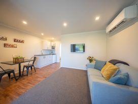 A living room with a sofa and a dining table at Mustering - Te Anau Holiday Home in Te Anau