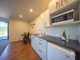 A kitchen with a sink, microwave, and dining table at Mustering - Te Anau Holiday Home in Te Anau