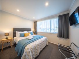 A bedroom with a bed and television at Mustering - Te Anau Holiday Home, Te Anau