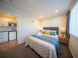 A bedroom with a bed and kitchenette at Mustering - Te Anau Holiday Home Te Anau