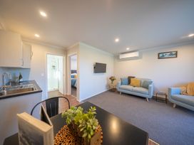 A living room with a sofa and television at Mustering - Te Anau Holiday Home, Te Anau