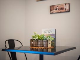 A dining area with a table, plant, book and mat at Mustering - Te Anau Holiday Home in Te Anau